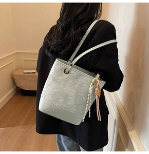 Detail of light blue embossed tote bag with floral patterns and woven charm strap
