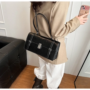 Detail of minimalist black rectangle shoulder bag with silver buckle and smooth leather finish