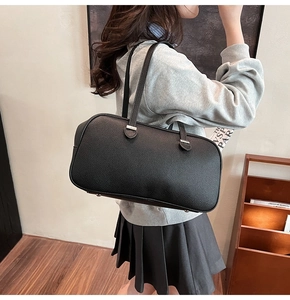Detailed back view of a black pebble leather underarm bag worn on a woman's shoulder