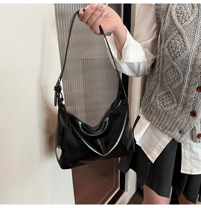 Détail du sac hobo noir brillant avec breloque cœur argentée sur un style décontracté