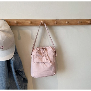 Dettaglio della borsa a secchiello rosa con coulisse appesa con cappello e jeans