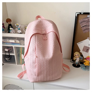 Detailed view of pink backpack with unique wavy texture and front zipper pocket detail