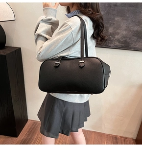 Detail view of black pebble leather shoulder bag with silver hardware and bottom feet