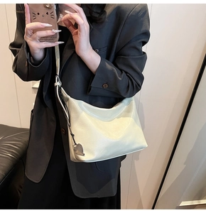 Sac sous le bras beige chic de forme croissant minimaliste avec détail pendentif cœur