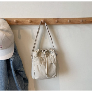 Borsa a secchiello beige minimalista con coulisse appesa su supporto di legno