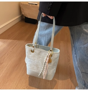 Detail of light blue embossed bucket bag with star patterns and woven pendant