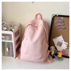 Close-up of pink backpack featuring textured leaf-like pattern on a desk setting