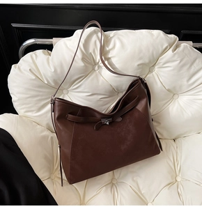 Detail of dark brown leather tote bag featuring a vintage metal clasp and matte finish