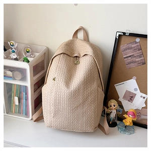 Close-up of cream backpack with distinctive woven texture and minimalist round design