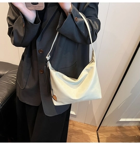 Détail du sac sous le bras en cuir blanc cassé avec pendentif cœur sur mannequin