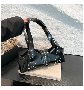 Detail van een zwarte laklederen baguette tas met zilveren klinknagels en Y2K vintage stijl