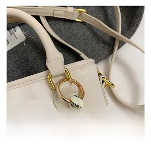Detailed close-up of golden hardware accents and woven strap on beige bucket bag