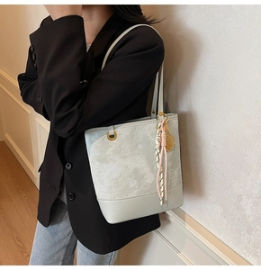 Light blue faux leather tote with star embossing shown on shoulder in lifestyle scene