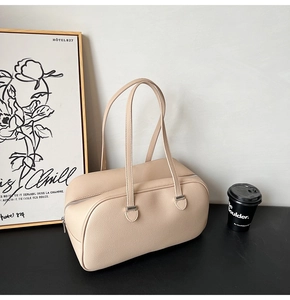 Detail of minimalist beige lychee leather boston bag with silver hardware and long handles