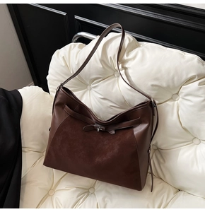 Detail of dark brown tote featuring mixed matte suede and glossy leather with silver clasp