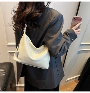 Détail du sac hobo en similicuir brillant blanc avec un pendentif en forme de cœur