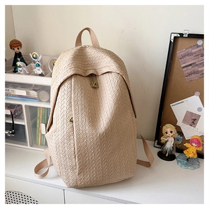 Detail of beige textured fabric backpack with metal triangle zipper on a desk