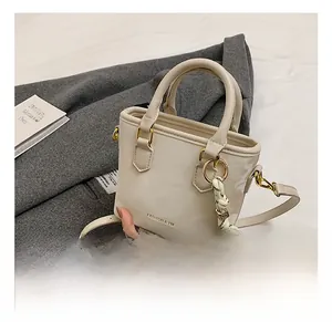 Detail of cream leather mini tote bag with gold metal ball charm and shoulder strap