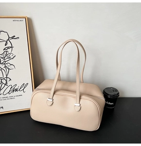 Close-up of beige lychee grain leather underarm bag with silver hardware on black desk