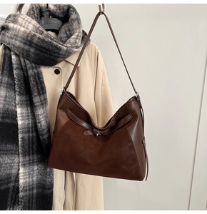 Detail of dark brown tote bag featuring mixed textures and elegant metal clasp