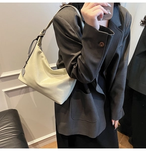 Détail du sac beige en cuir souple avec pendentif en forme de cœur et finitions à franges