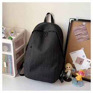 Detail of black backpack featuring a unique 3D woven texture on the surface in a study setting