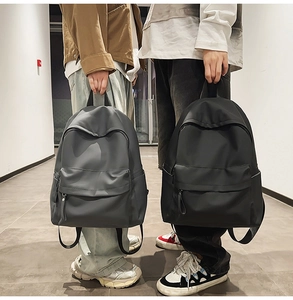 Minimalist waterproof nylon backpack in grey and black shown in a lifestyle corridor setting