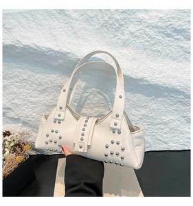 Detailopname van de witte kunstlederen draagtas met decoratieve zilveren studs op de hengsels