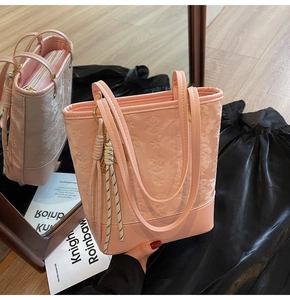 Detail of pink shoulder bag with star and letter embossing and braided rope accent