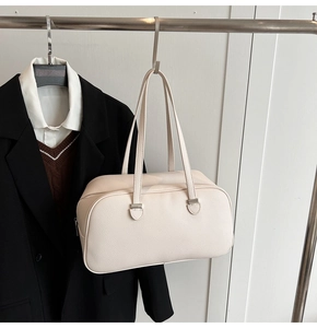 Detail of off-white lychee grain leather boston bag hung with a blazer for styling