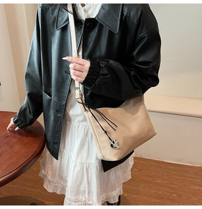 Vue détaillée du sac sous le bras en cuir abricot avec un pendentif cœur en métal argenté