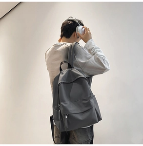 Detail of dark grey waterproof nylon backpack with front zipper pocket on a model