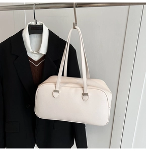 Detail of minimalist cream leather bowling bag texture and silver metal hardware