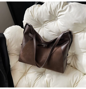 Detail of a brown leather tote bag with suede paneling and metal turn-lock closure