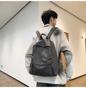 Rear view of a dark grey minimalist backpack with adjustable straps and front flap pocket