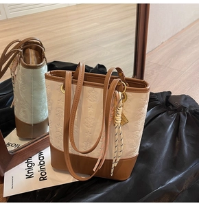 Detail of white embossed floral tote bag with brown leather straps and metal zipper