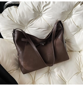 Macro shot of dark brown leather tote bag with metallic twist lock on sofa