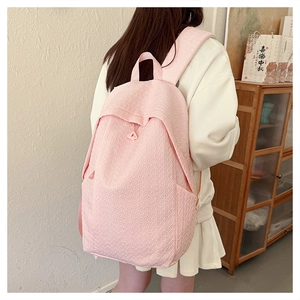 Close-up of pink backpack with leaf embossed texture and side pocket detail on a person