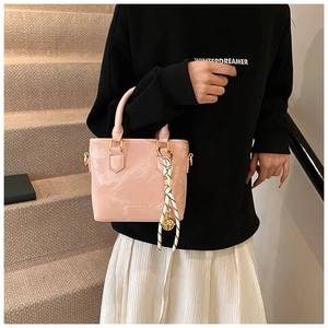 Detail of pink marble pattern handbag with gold hardware and a striped scarf accessory