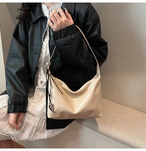 Détail du sac sous le bras crème avec pendentif cœur argenté en similicuir plissé