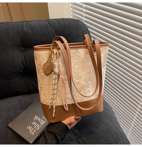Close-up of cream embossed tote bag with star patterns and brown leather strap detail