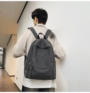 Rear view of minimalist dark grey waterproof nylon backpack worn on a model