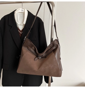Detail of a brown leather and suede tote bag with a decorative silver twist lock and strap