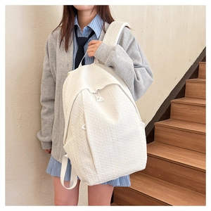 Detail of white large capacity backpack with textured diamond pattern and padded straps