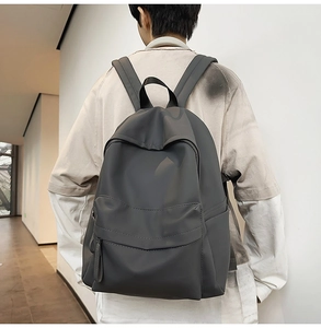 Rear view of a dark grey minimalist backpack on a person showing sleek waterproof fabric