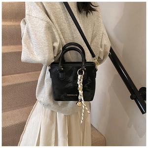 Detail of black textured bucket bag with silk scarf and gold hardware on fashion model