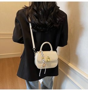 Close-up of saddle bag with gold clasp and polka dot scarf detail on the handle