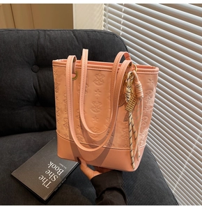 Detailed pink tote bag with embossed star patterns and decorative woven charm