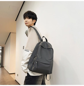 Detail view of large capacity dark grey backpack featuring a zippered front pocket and side slots