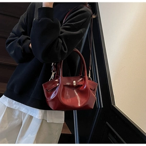 Dettaglio borsa tote in vernice bordeaux con pieghe e chiusura in metallo oro
